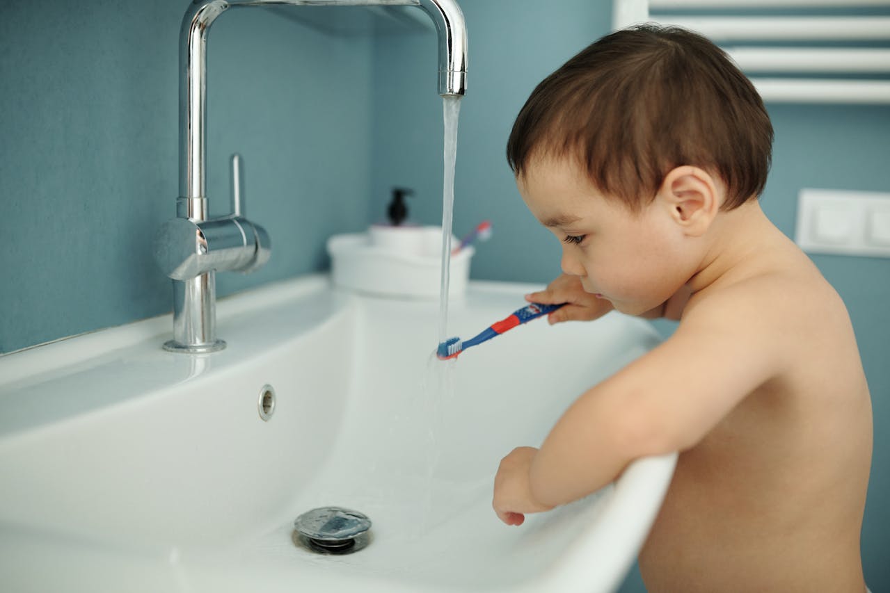 Kleiner Junge hält eine Zahnbürste unter Wasser