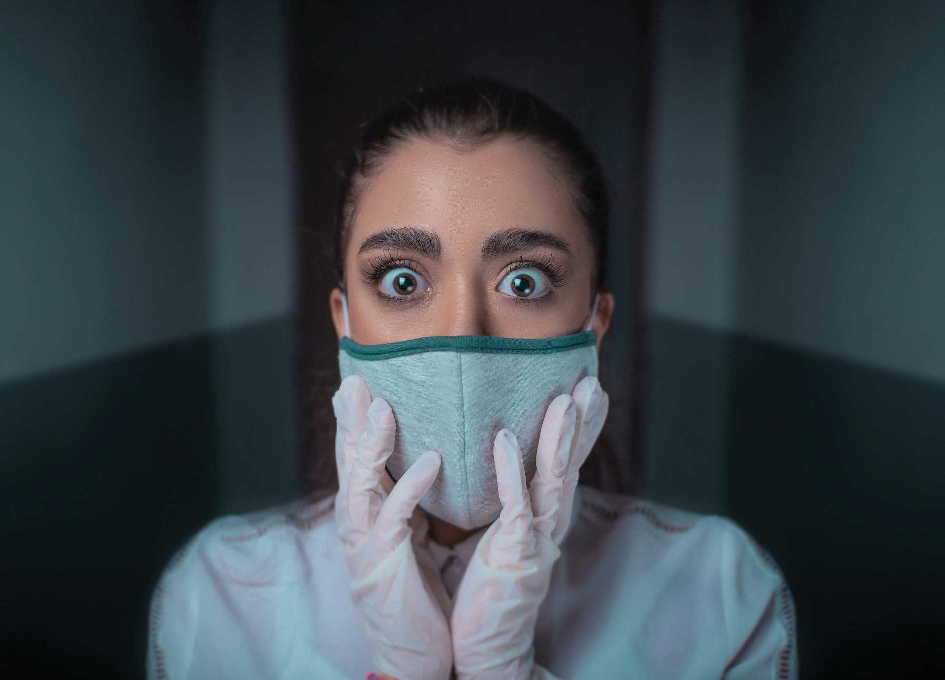 Frau mit Mundschutzmasken und erschrockenem Gesicht.