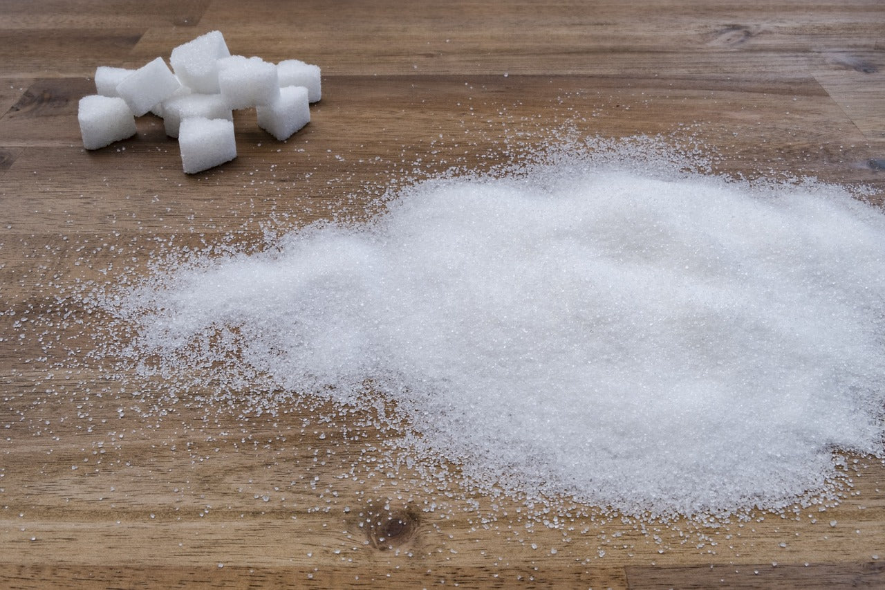Zuckerwürfel und verstreuter Zucker auf hölzernem Tisch